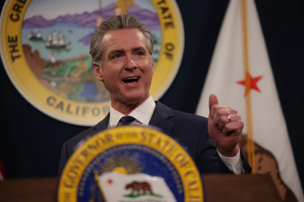 Le gouverneur Gavin Newsom s'adressant à un public derrière un pupitre officiel, avec le sceau de la Californie en arrière-plan.