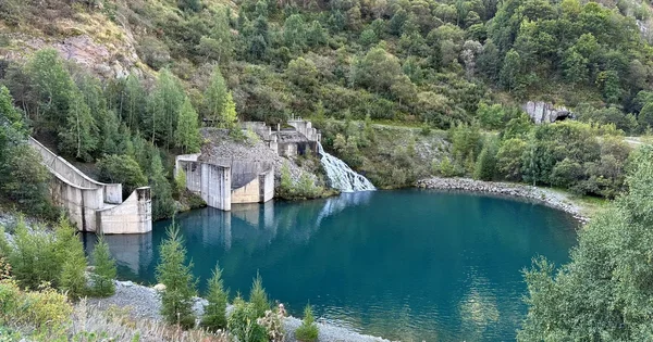 Barrage hydroélectrique avec déversement d'eau dans un réservoir turquoise, au cœur de la nature.