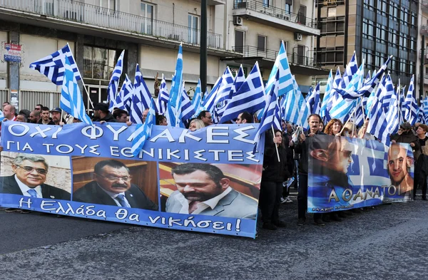 Rassemblement de soutien à l'Aube Dorée avec drapeaux grecs et portraits de dirigeants.