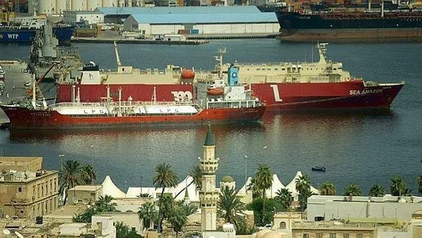 Cargos rouges dans un port libyen, avec un minaret en arrière-plan.