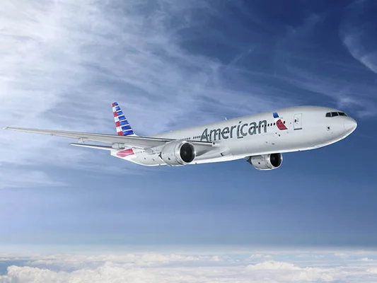 Un Boeing 777 d'American Airlines en vol dans un ciel bleu nuageux.