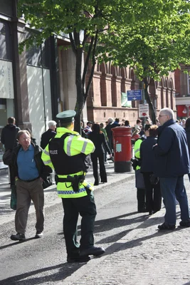 Policier du PSNI en patrouille dans une zone urbaine animée.