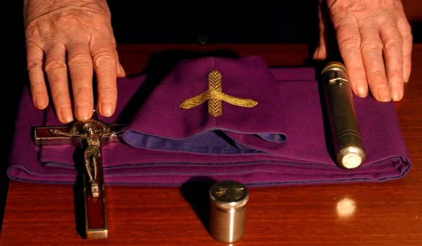 Mains d'un prêtre exorciste avec crucifix et étole, symboles de son ministère.