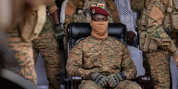 Un officier militaire burkinabè en tenue de combat, entouré de soldats.