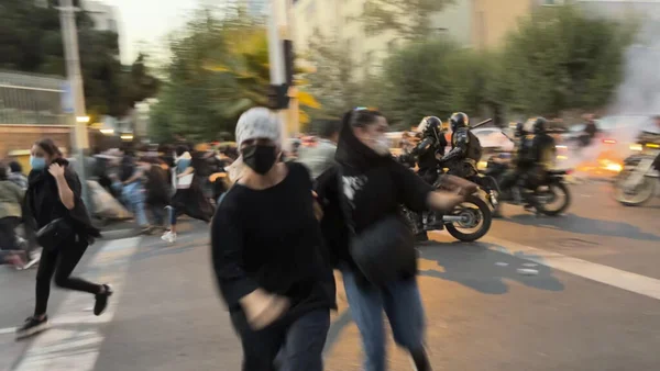 Scène de protestation en Iran, montrant des manifestants fuyant les forces de l'ordre.