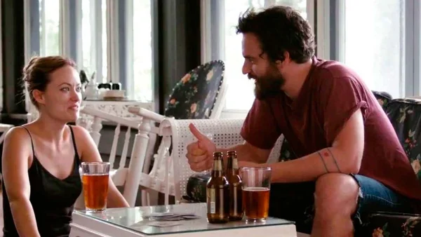 Olivia Wilde et Jake Johnson dans une scène de « Drinking Buddies », discutant autour d'une table.