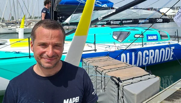 Ambrogio Beccaria, vainqueur de la Vendée Arctique, posant devant son voilier 'Allagrande Mapei'.