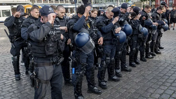 Des policiers en tenue anti-émeute rendent hommage lors d'un rassemblement après une attaque meurtrière.