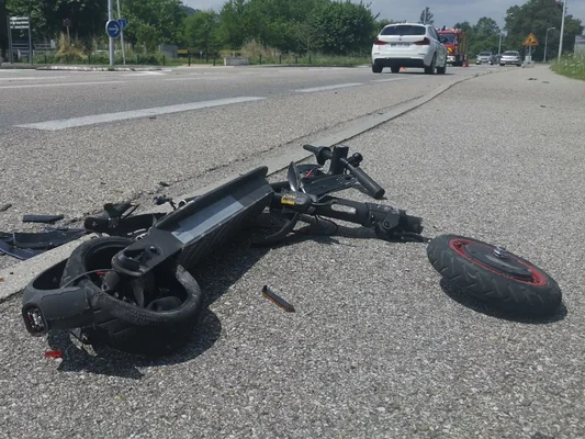 Trottinette électrique accidentée sur le bord de la route, illustrant les risques liés à l'absence d'assurance.