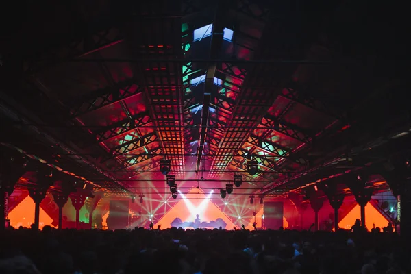 Festivaliers du Peacock Society sous les lumières rouges et orange d'un hangar du Parc Floral en 2015.