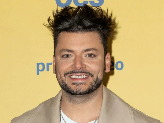 Kev Adams pose souriant, affichant son nouveau physique après sa perte de poids.