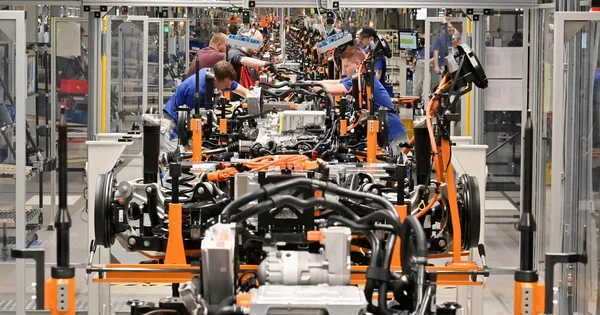 Ouvriers assemblant des composants électriques sur des châssis de véhicules Volkswagen
