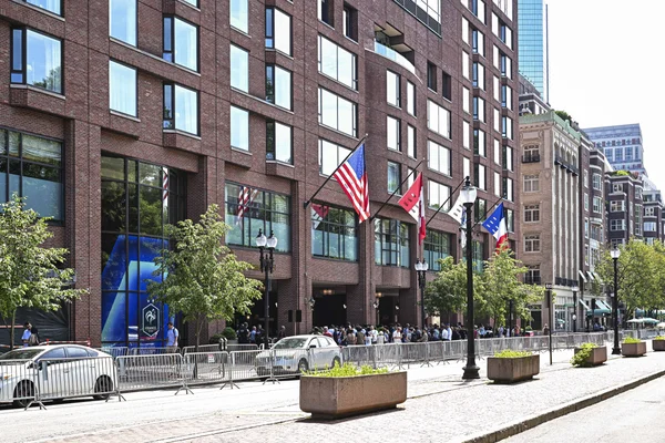 Foule rassemblée devant l'hôtel des Bleus à Boston, avec drapeaux américains et canadiens.