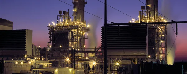 Complexe industriel gazier illuminé au crépuscule.