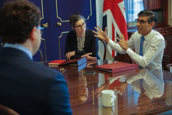 Réunion autour d'une table en bois avec le drapeau britannique en arrière-plan.