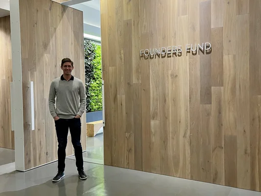 Un entrepreneur associé à Founders Fund devant le mur emblématique de l'entreprise.