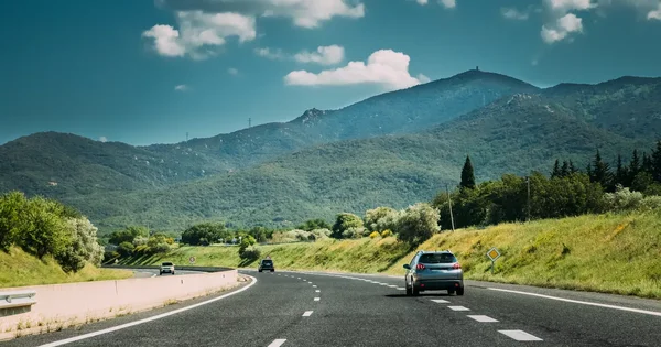 Un SUV parcourt une route de montagne vers les Pyrénées, évoquant le déplacement des vacanciers.