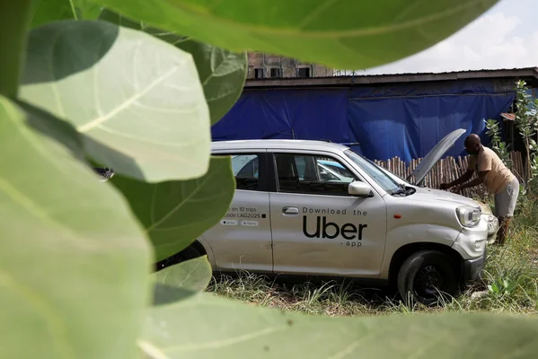 Un conducteur Uber inspectant le moteur de son véhicule.