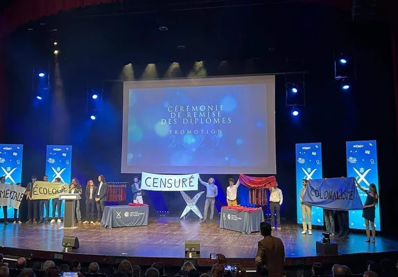 Des étudiants manifestent pendant la cérémonie de remise des diplômes à Polytechnique avec des pancartes « CENSURÉ » et « COLONIALISME ».