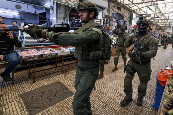 Patrouille de soldats israéliens dans un marché couvert en Cisjordanie.
