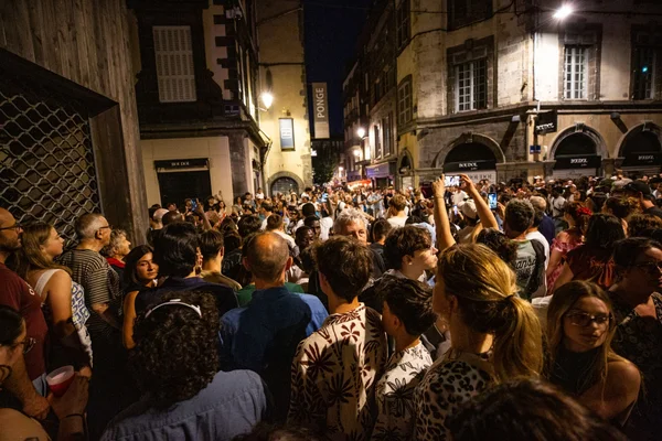 Foule dans une rue étroite lors de la Fête de la musique, avec des téléphones levés.