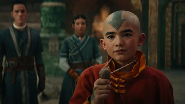 Aang, l'Avatar, dans un temple ou palais, entouré d'autres personnages.