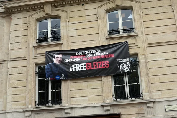 Bannière de soutien à Christophe Gleizes accrochée à un bâtiment classique en pierre.