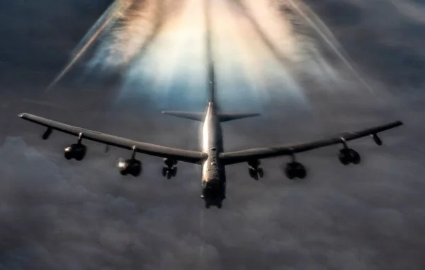 Un B-52 Stratofortress en plein vol, photographié depuis le sol avec un effet de traînée lumineuse.