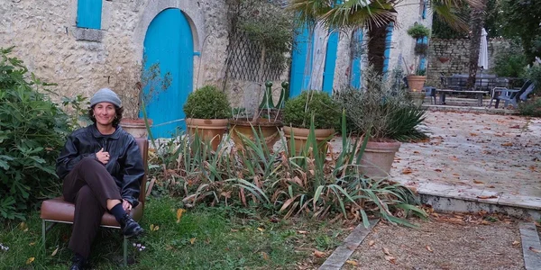 Elisa Routa dans un jardin, vêtue d'un bonnet et d'une veste en cuir.