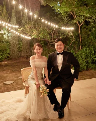 Ko Kyu Phil et Amin lors de leur mariage, assis sous des guirlandes lumineuses.
