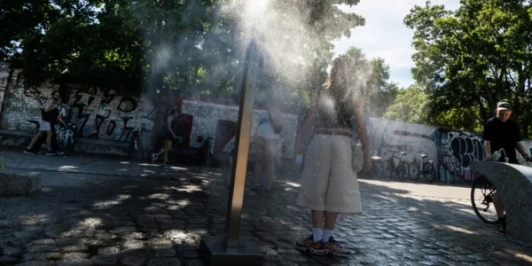 Un passant se rafraîchit sous un brumisateur public lors d'une canicule.
