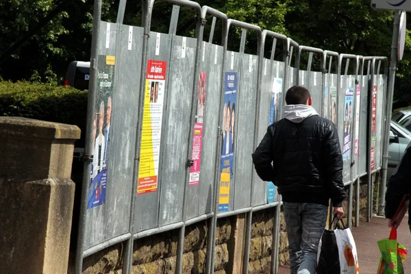 Campagne électorale : un passant devant des affiches politiques.