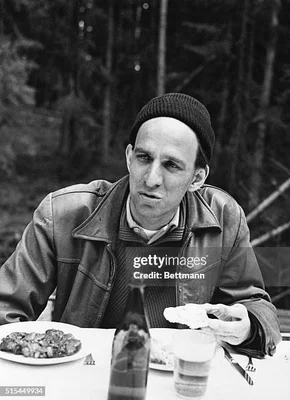 Ingmar Bergman attablé en extérieur, photographié en noir et blanc.