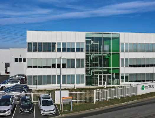 Le nouveau siège social de Mistral SAS, un immeuble moderne avec atrium vitré et logo visible.