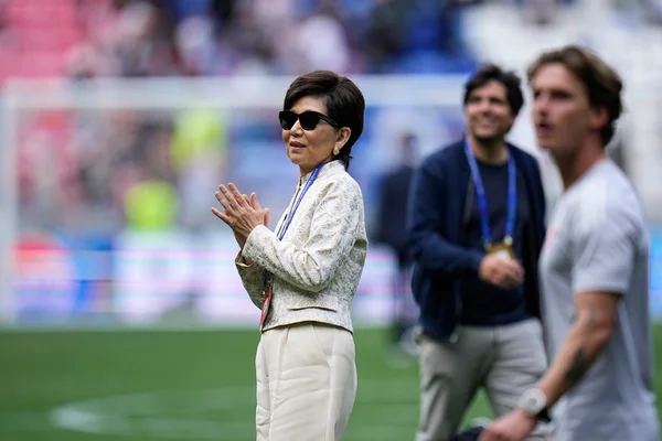 Michele Kang applaudit sur la pelouse d'un stade de football.
