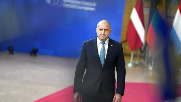 Un responsable bulgare marchant sur un tapis rouge, avec des drapeaux nationaux en arrière-plan.
