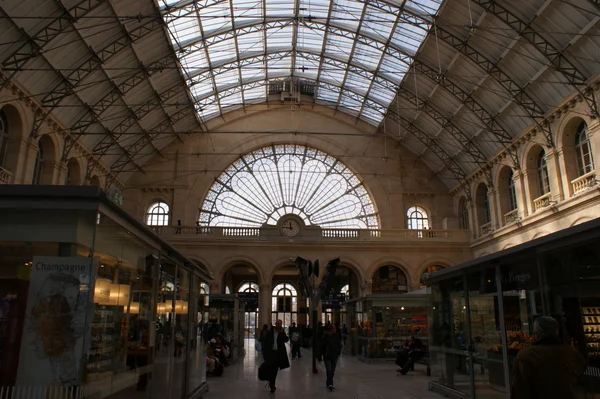 Intérieur de la gare de l'Est à Paris, avec sa verrière et ses voyageurs.