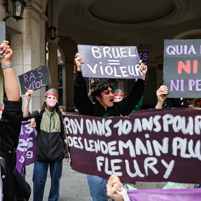 Une manifestante crie son indignation, pancarte « BRUEL = VIOLEUR » à la main.