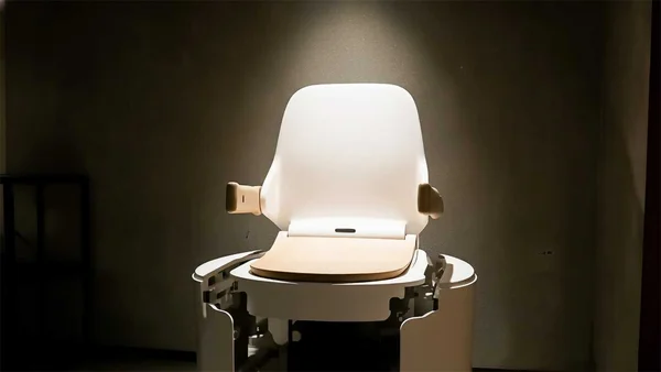 Robot toilette exposé sous projecteur, montrant ses mécanismes internes.