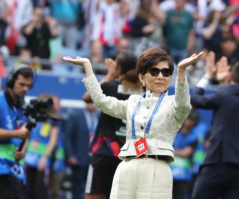 Michele Kang, dans la foule, lève les mains lors d'un match au stade.