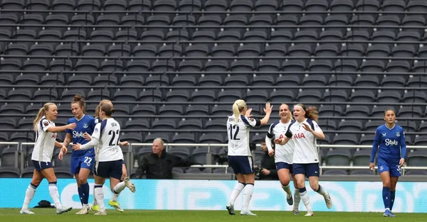 Les joueuses de Tottenham Hotspur célébrant un but sur la pelouse, maillots blancs et bleus.