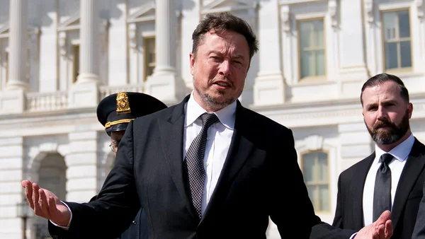 Elon Musk gesticulant devant la Maison-Blanche, entouré de sécurité.