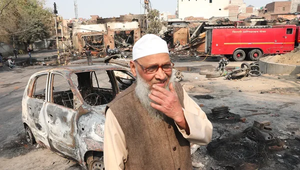 Un homme âgé devant une voiture calcinée après des violences anti-musulmanes en Inde.