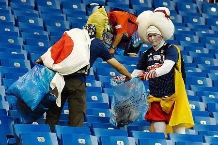 Des supporters japonais costumés participent au nettoyage des tribunes après un match.