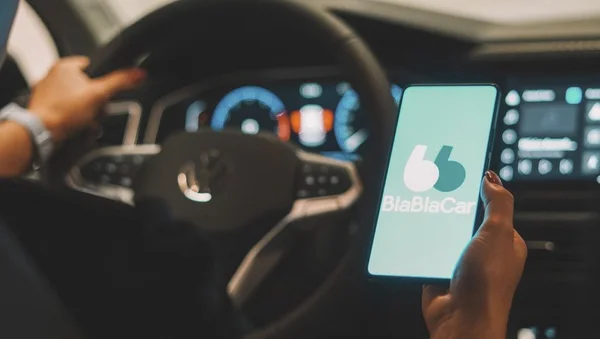 À bord d'un véhicule, un conducteur et un passager utilisent l'application BlaBlaCar pour covoiturer.