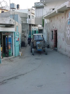 Rue d'Al-Yamoun avec un tracteur bleu et des passants.