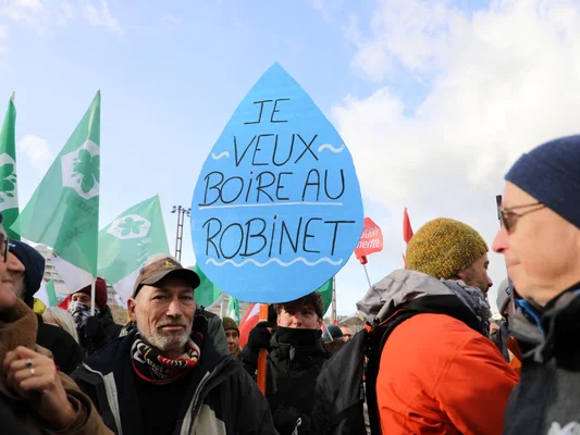 Manifestant portant une pancarte en forme de goutte d'eau avec le slogan « Je veux boire au robinet » à Rennes.