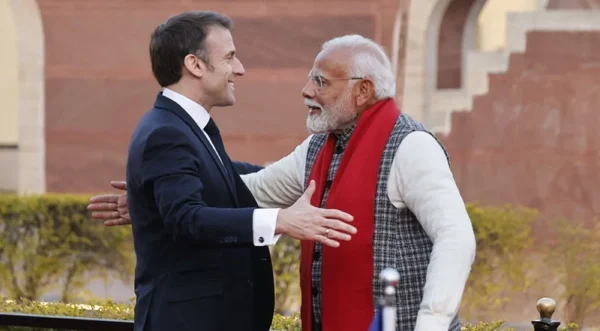 Emmanuel Macron et Narendra Modi échangeant une poignée de main lors d'une rencontre en extérieur.