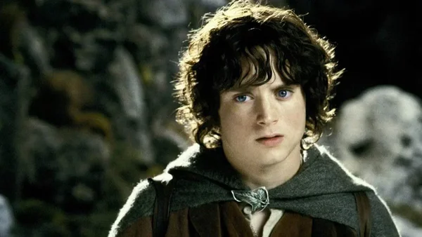 Elijah Wood dans le rôle de Frodon Sacquet, vêtu d'une cape grise et d'une broche elfique.
