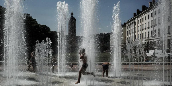 Des enfants se rafraîchissent dans une fontaine lors d'une journée de canicule en France.